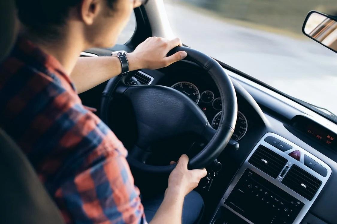 Young male driving car with black interior.