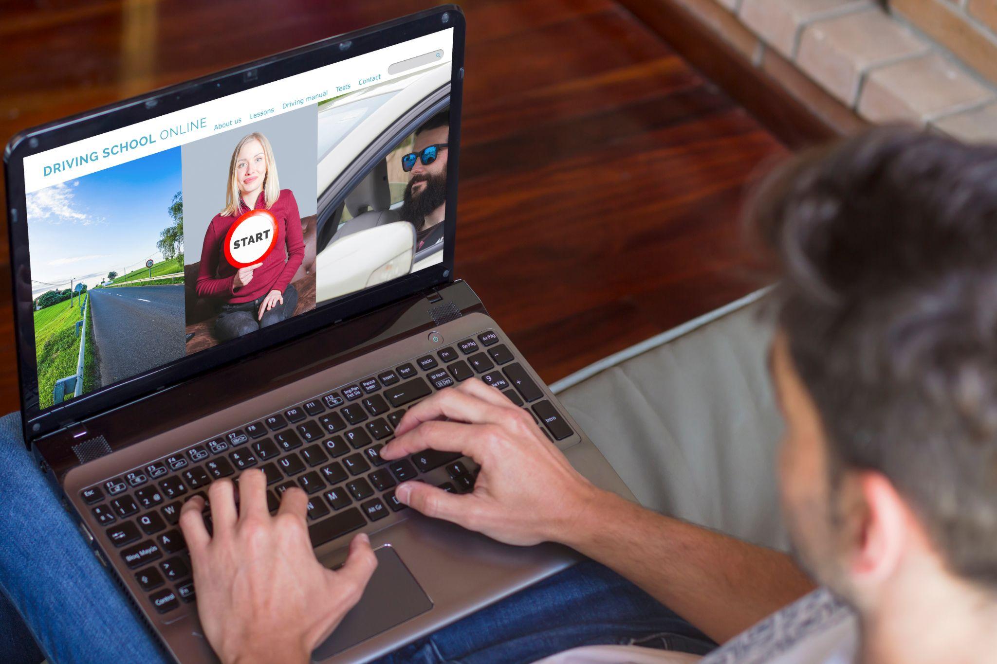 Young man at home using laptop with driving school website on the screen